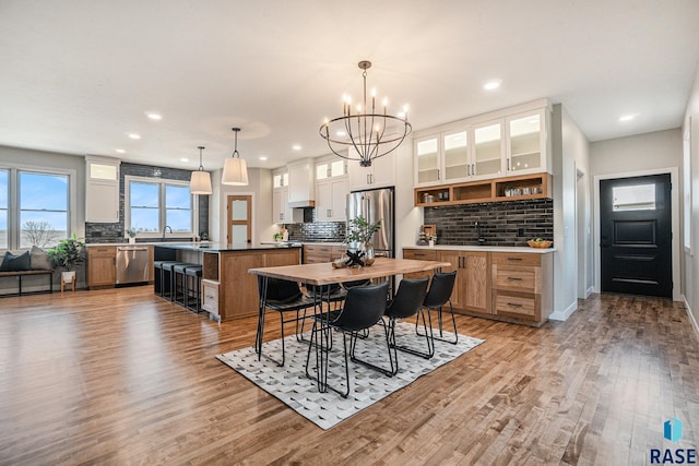 dining area with light wood-type flooring and an inviting chandelier