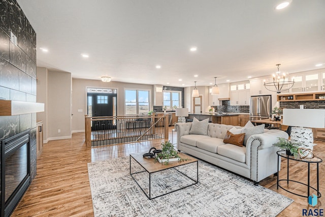 living room featuring light hardwood / wood-style flooring, a tile fireplace, and a chandelier