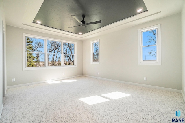 empty room with carpet flooring, ceiling fan, and a tray ceiling