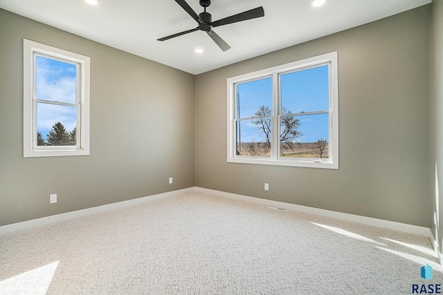 empty room featuring ceiling fan, plenty of natural light, and carpet