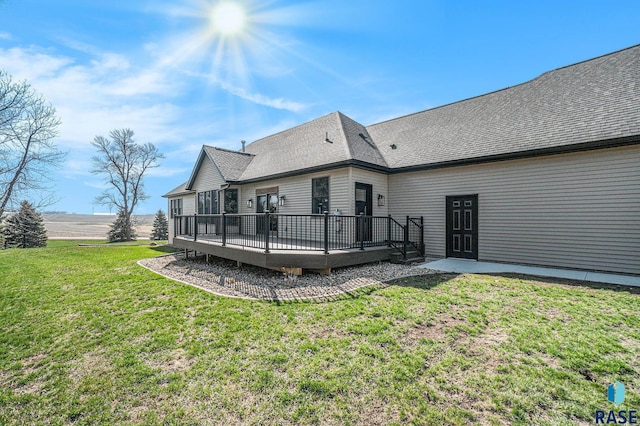 rear view of house featuring a deck and a lawn