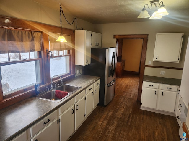 kitchen with white cabinetry, sink, pendant lighting, and stainless steel refrigerator with ice dispenser