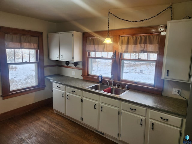 kitchen featuring white cabinets, decorative light fixtures, dark hardwood / wood-style floors, and sink