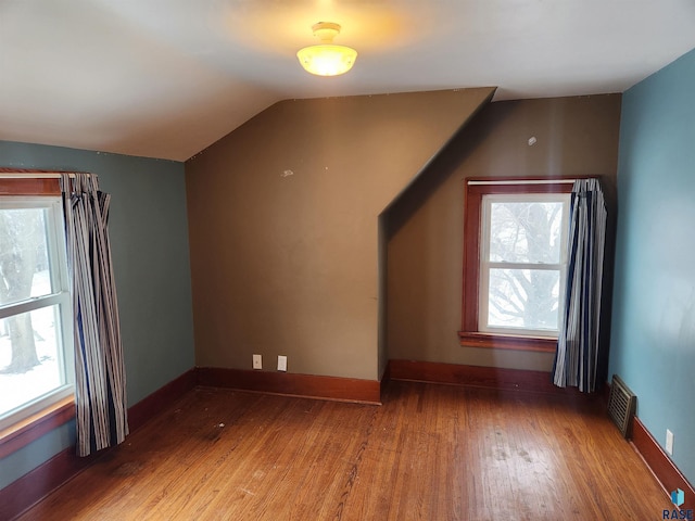 bonus room with hardwood / wood-style floors and vaulted ceiling