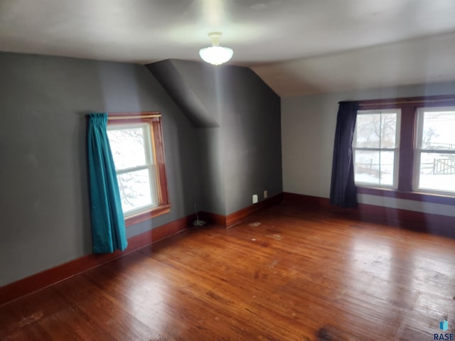 bonus room with dark wood-type flooring and vaulted ceiling