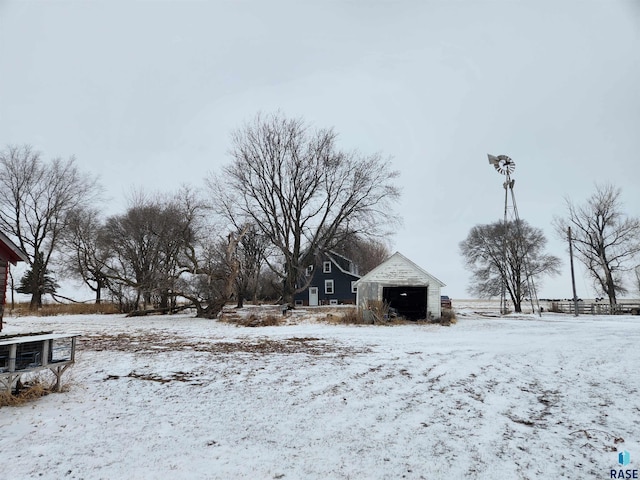 yard layered in snow featuring an outbuilding and a garage