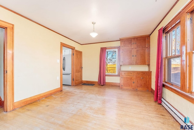 interior space with ornamental molding, baseboard heating, a wealth of natural light, and light hardwood / wood-style flooring