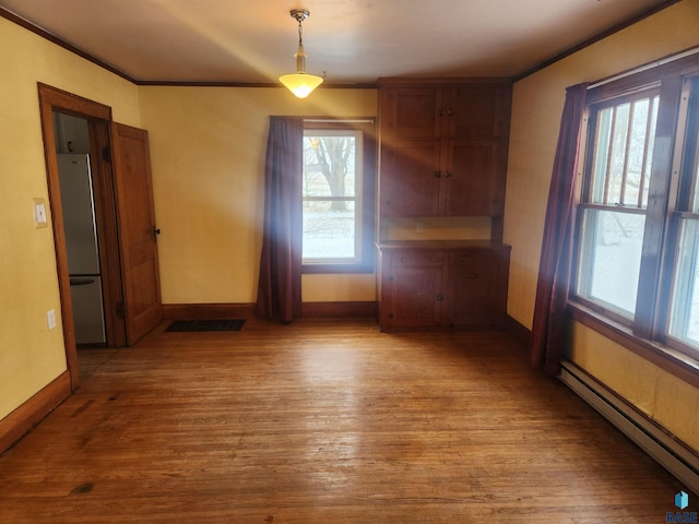 unfurnished dining area with light hardwood / wood-style flooring, a baseboard heating unit, and crown molding