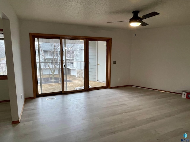 unfurnished room featuring ceiling fan, light hardwood / wood-style floors, and a textured ceiling