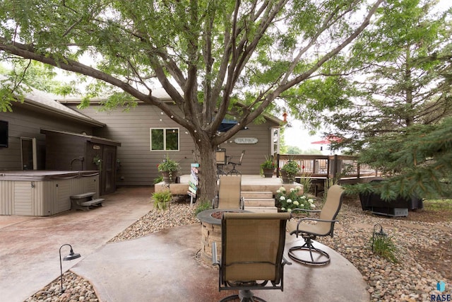 view of patio featuring a hot tub, a deck, and a fire pit