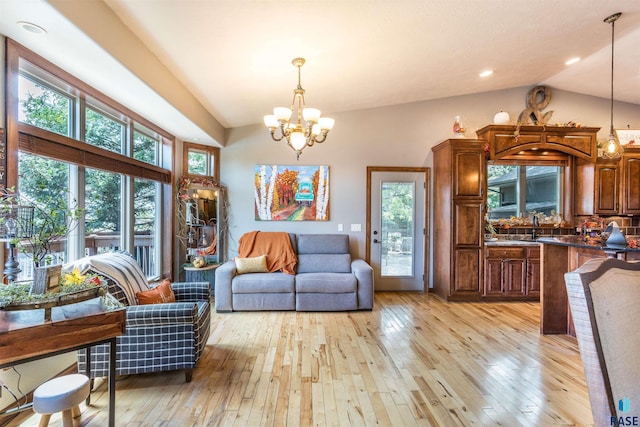 living room with a notable chandelier, lofted ceiling, sink, and light wood-type flooring