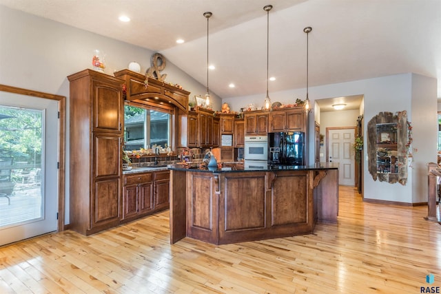 kitchen featuring sink, decorative light fixtures, black refrigerator with ice dispenser, and a center island with sink