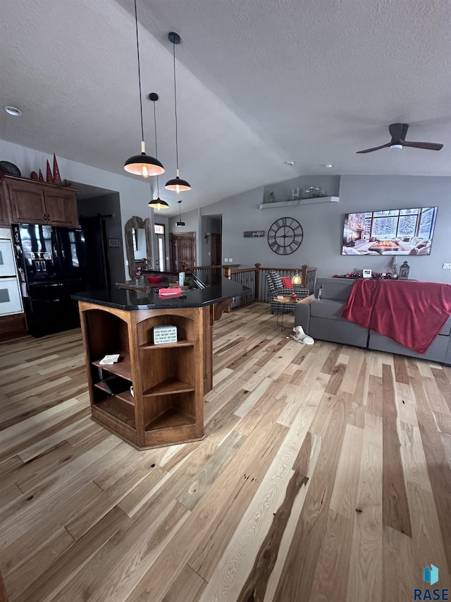 kitchen featuring vaulted ceiling, decorative light fixtures, light wood-type flooring, and black refrigerator with ice dispenser