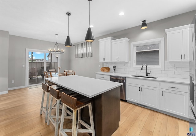 kitchen with white cabinetry, a center island, stainless steel dishwasher, a breakfast bar area, and decorative backsplash