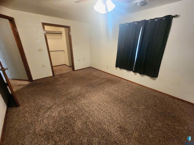 unfurnished bedroom featuring carpet, a walk in closet, a closet, and ceiling fan