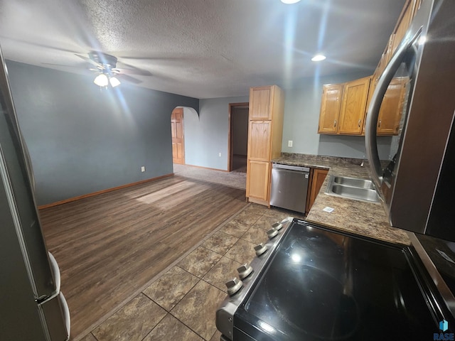 kitchen featuring appliances with stainless steel finishes, a textured ceiling, ceiling fan, sink, and dark hardwood / wood-style floors