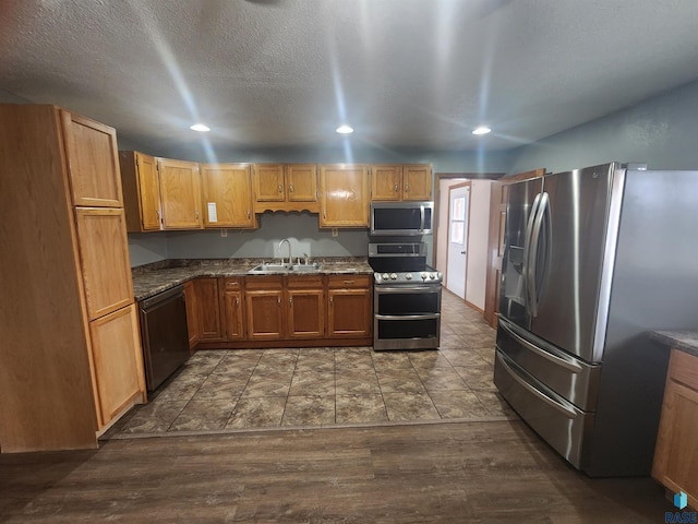 kitchen with a textured ceiling, stainless steel appliances, dark hardwood / wood-style floors, and sink