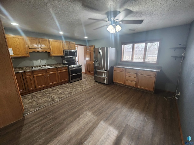 kitchen with appliances with stainless steel finishes, a textured ceiling, ceiling fan, sink, and dark hardwood / wood-style floors