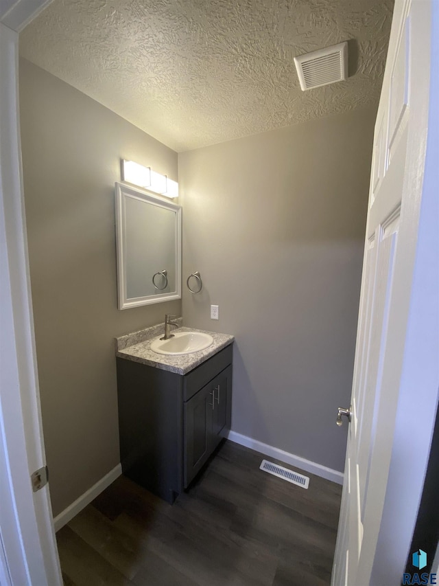 bathroom with wood-type flooring, vanity, and a textured ceiling