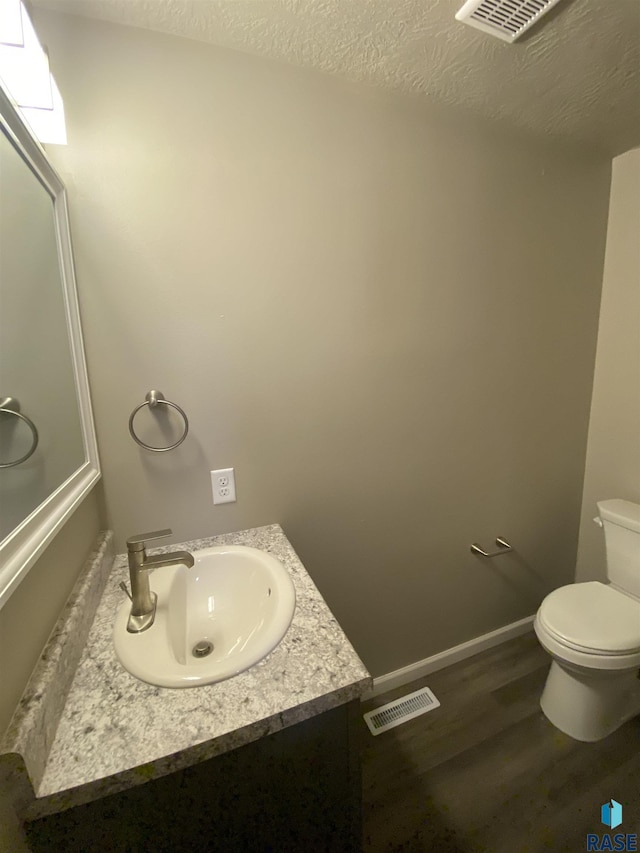 bathroom with vanity, a textured ceiling, hardwood / wood-style flooring, and toilet