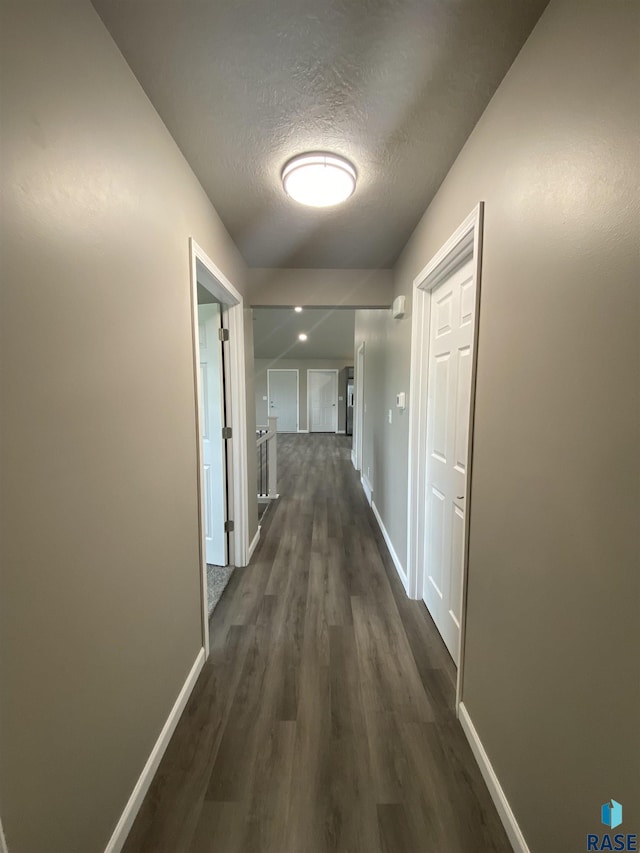 hall with dark wood-type flooring and a textured ceiling