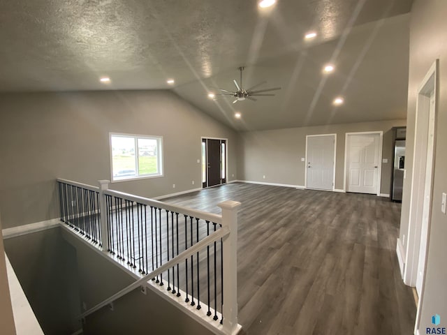 interior space featuring ceiling fan, dark hardwood / wood-style flooring, lofted ceiling, and a textured ceiling