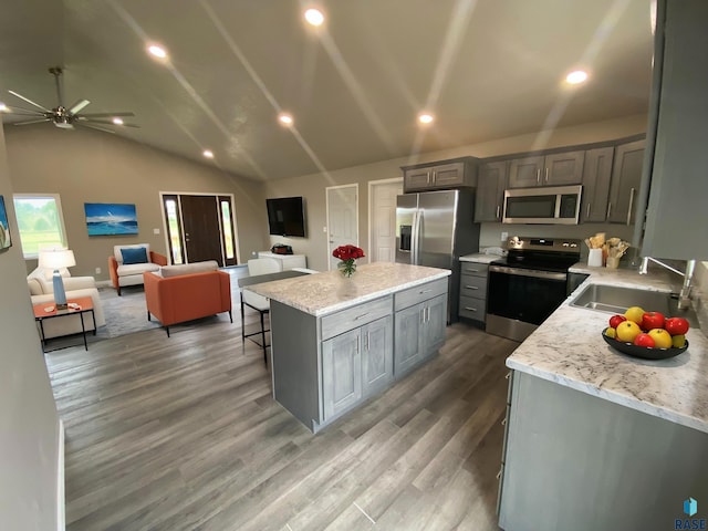 kitchen featuring a breakfast bar area, gray cabinetry, a kitchen island, and appliances with stainless steel finishes