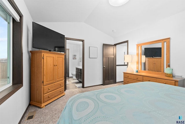 bedroom with light carpet, ensuite bath, and lofted ceiling