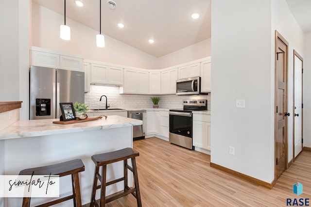 kitchen featuring white cabinetry, sink, hanging light fixtures, stainless steel appliances, and kitchen peninsula