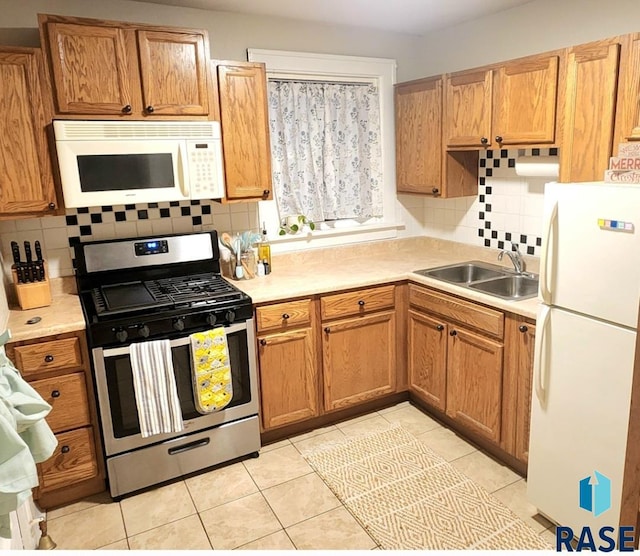 kitchen with tasteful backsplash, white appliances, sink, and light tile patterned floors