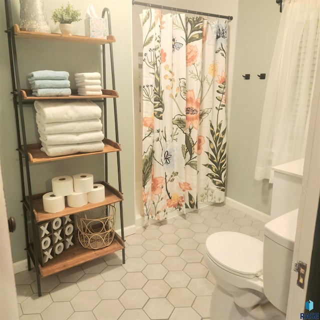 bathroom featuring a shower with shower curtain, toilet, and tile patterned flooring