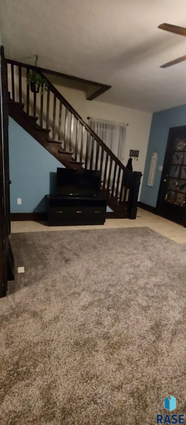 stairs with ceiling fan and carpet flooring