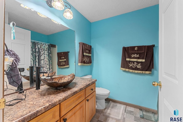 bathroom with a shower with shower curtain, vanity, toilet, and a textured ceiling