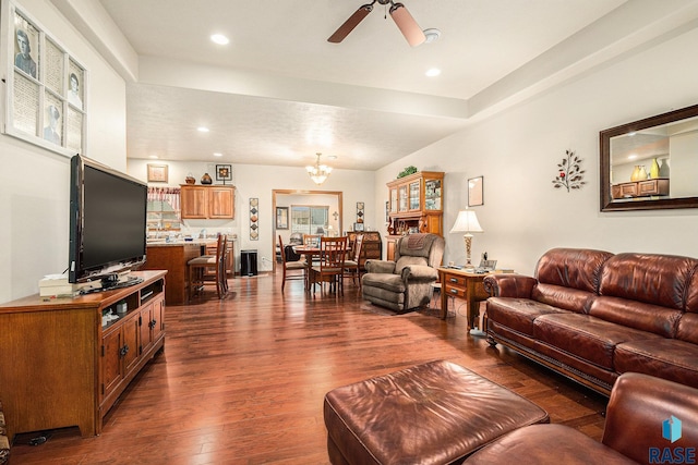 living room with ceiling fan with notable chandelier and dark hardwood / wood-style flooring