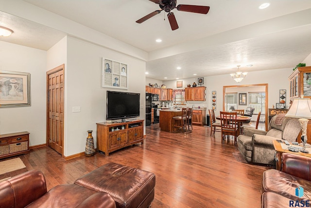 living room with ceiling fan with notable chandelier and dark hardwood / wood-style floors