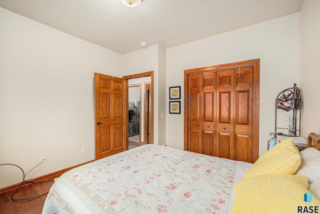 bedroom with washer / dryer, hardwood / wood-style flooring, and a closet