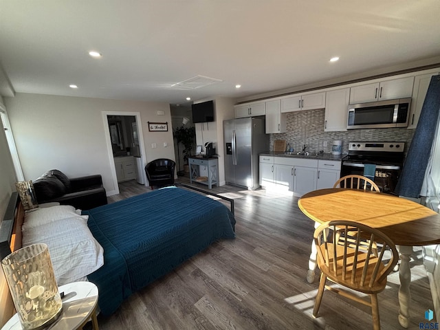 kitchen featuring sink, stainless steel appliances, dark hardwood / wood-style flooring, backsplash, and white cabinets