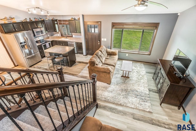 living room featuring light hardwood / wood-style floors, ceiling fan, and sink