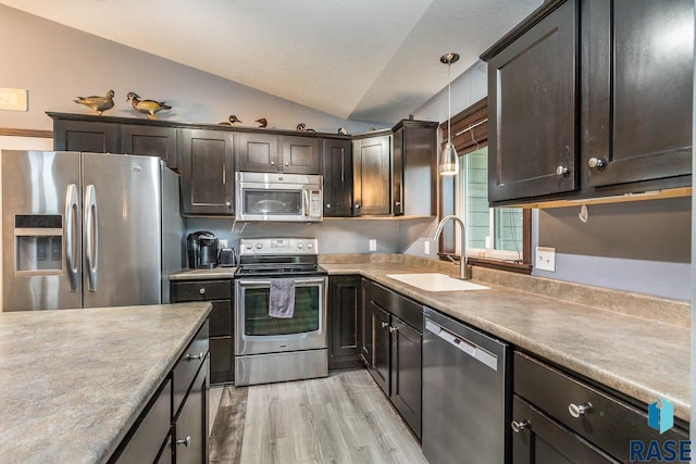 kitchen featuring appliances with stainless steel finishes, vaulted ceiling, sink, light hardwood / wood-style flooring, and hanging light fixtures