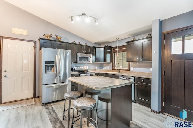 kitchen featuring a center island, hanging light fixtures, stainless steel appliances, light hardwood / wood-style floors, and lofted ceiling