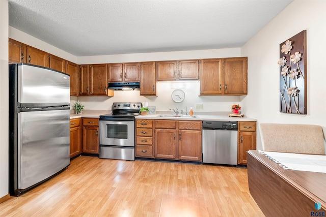 kitchen with sink, light hardwood / wood-style floors, a textured ceiling, and appliances with stainless steel finishes