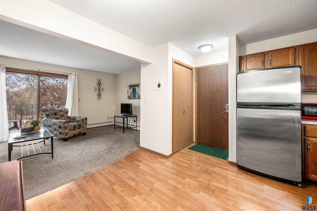 kitchen featuring a textured ceiling, stainless steel refrigerator, and light hardwood / wood-style flooring