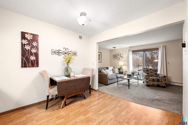 living room featuring baseboard heating, hardwood / wood-style floors, and a textured ceiling