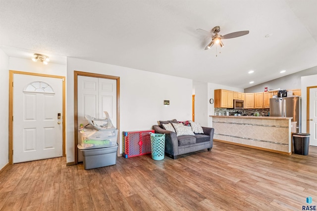 living room featuring ceiling fan, light hardwood / wood-style floors, and lofted ceiling