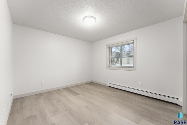 spare room with baseboard heating, light hardwood / wood-style flooring, and a textured ceiling