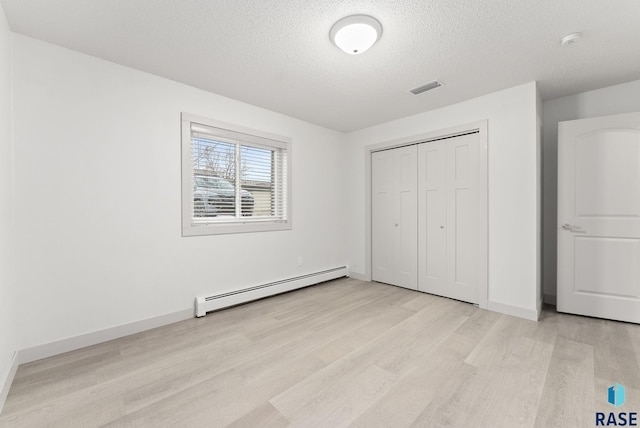 unfurnished bedroom with a textured ceiling, a baseboard radiator, a closet, and light hardwood / wood-style floors