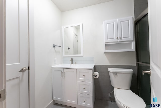 bathroom with vanity, toilet, and tile walls