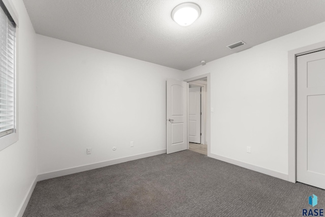 unfurnished bedroom with dark carpet and a textured ceiling