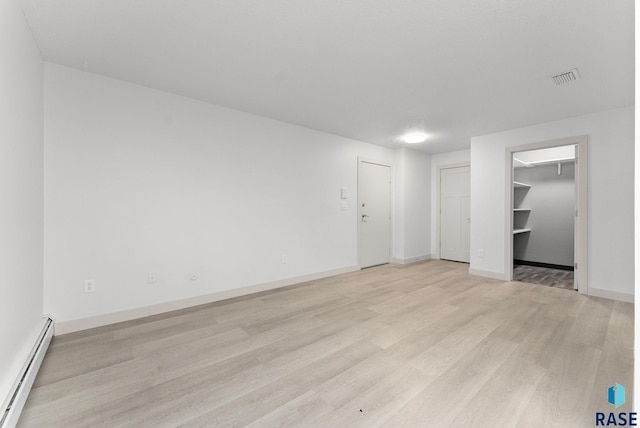 empty room with light hardwood / wood-style floors and baseboard heating