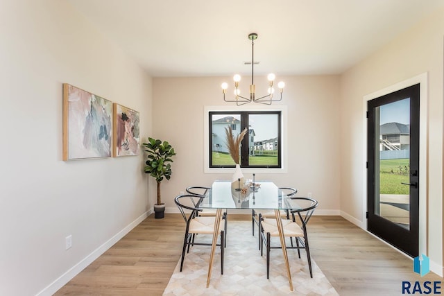 dining room with light hardwood / wood-style floors and an inviting chandelier